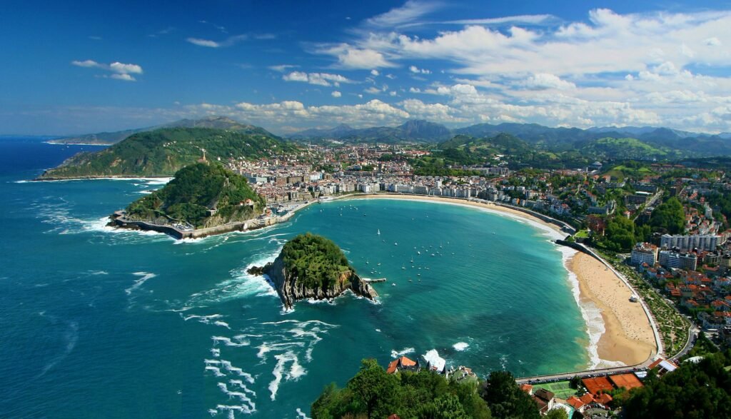 A panoramic view of La Concha Beach, surrounded by lush green hills and charming city buildings, making it one of Spain’s most scenic coastal spots.