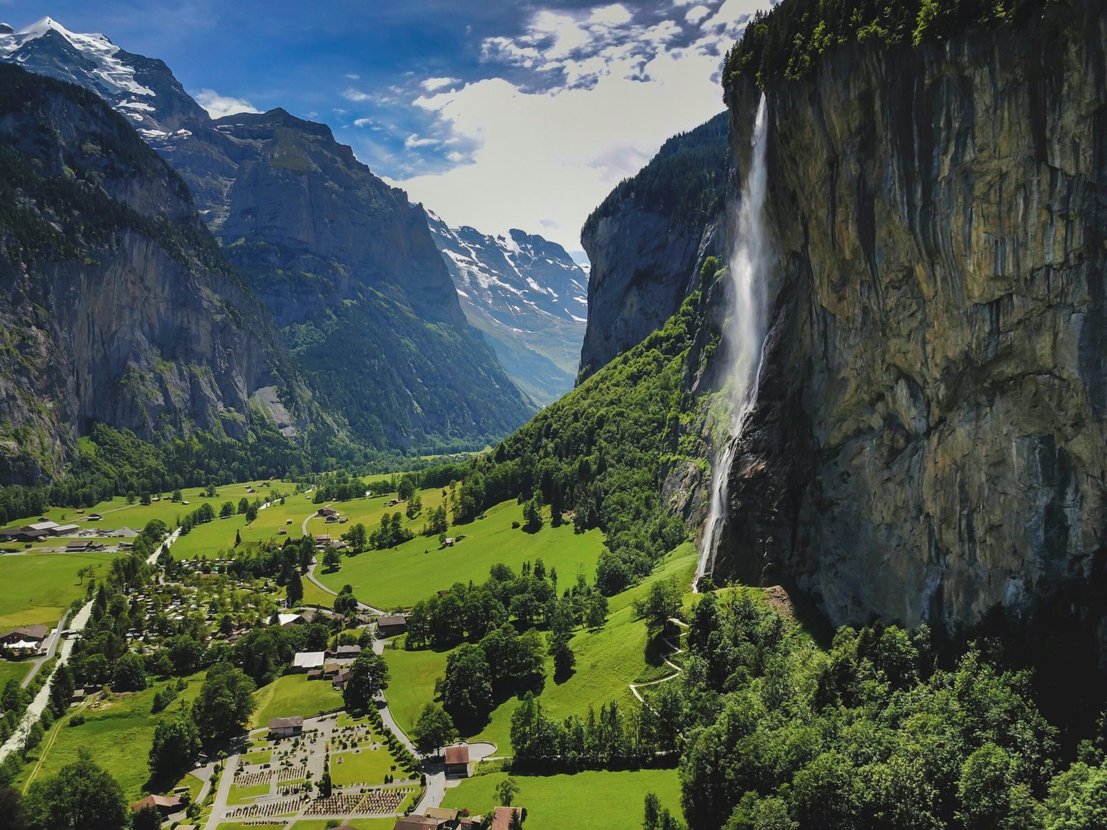 Breathtaking alpine scenery with a waterfall and lush green valley in Lauterbrunnen, Switzerland.